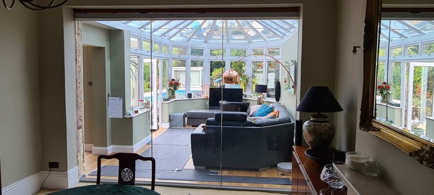 frameless room divider in Essex house with conservatory in the background 